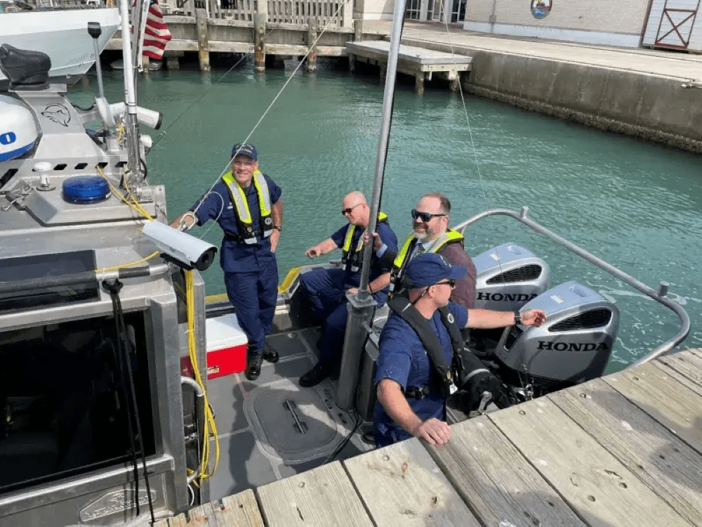 Three Department of Homeland Security personnel standing on a naval craft.