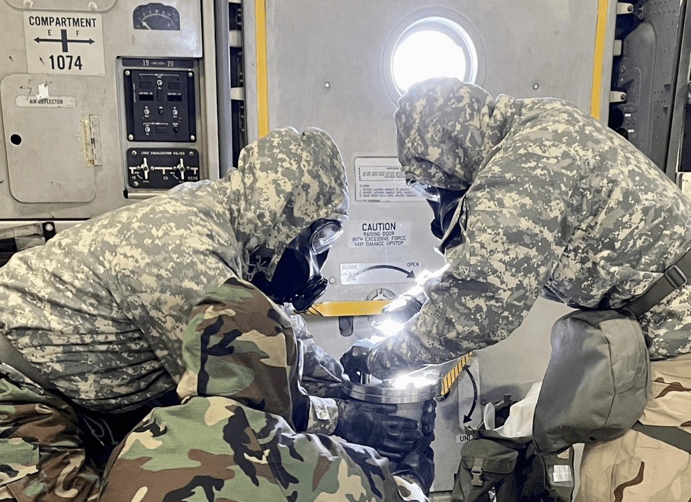 Military Personnel with protective equipment hold a container