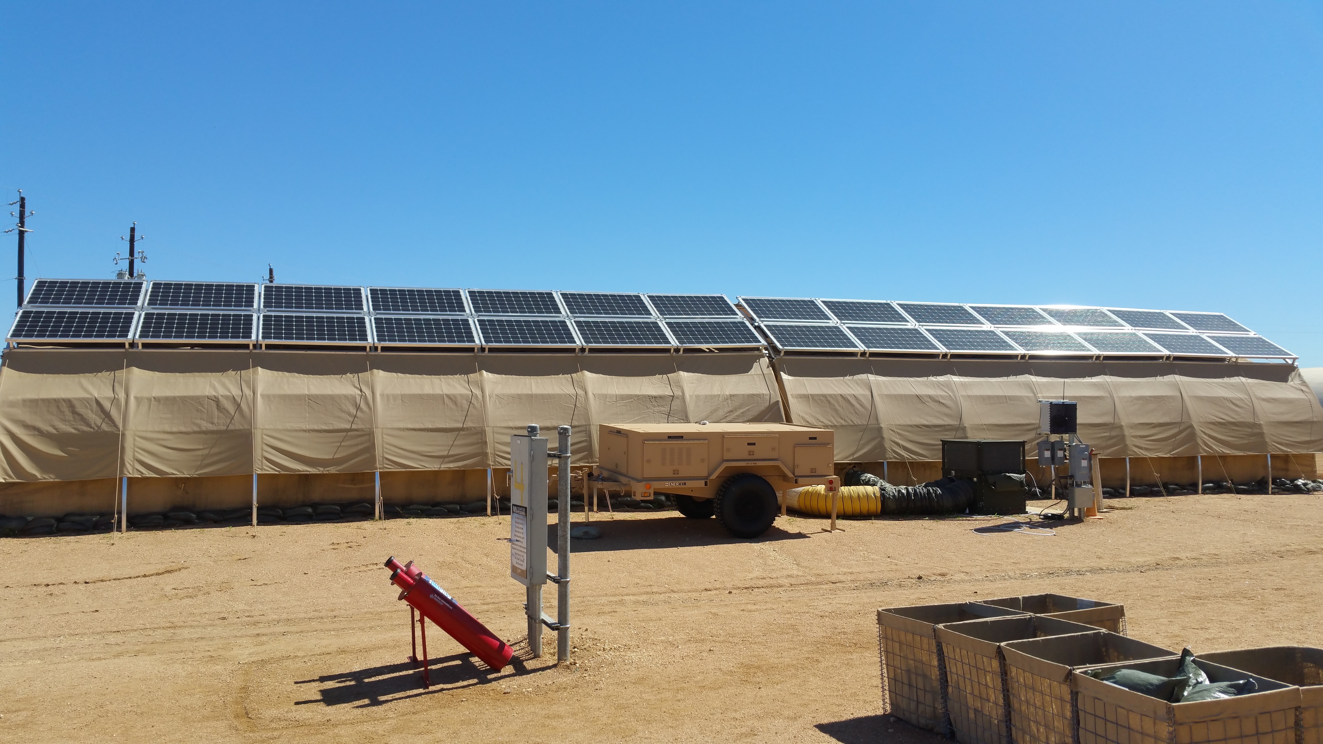 Figure 4. Monocrystalline Silicon Solar Panels Placed on Top of Each Tent for Energy Production. A Trailer (Center) Holds the Hardware, Software, and Lithium Ion Batteries That Form the Smart Grid and Provide Energy Backup Should the Grid Fail (Source: Photo by Donna M. Lindner, U.S. Air Force Research Laboratory).