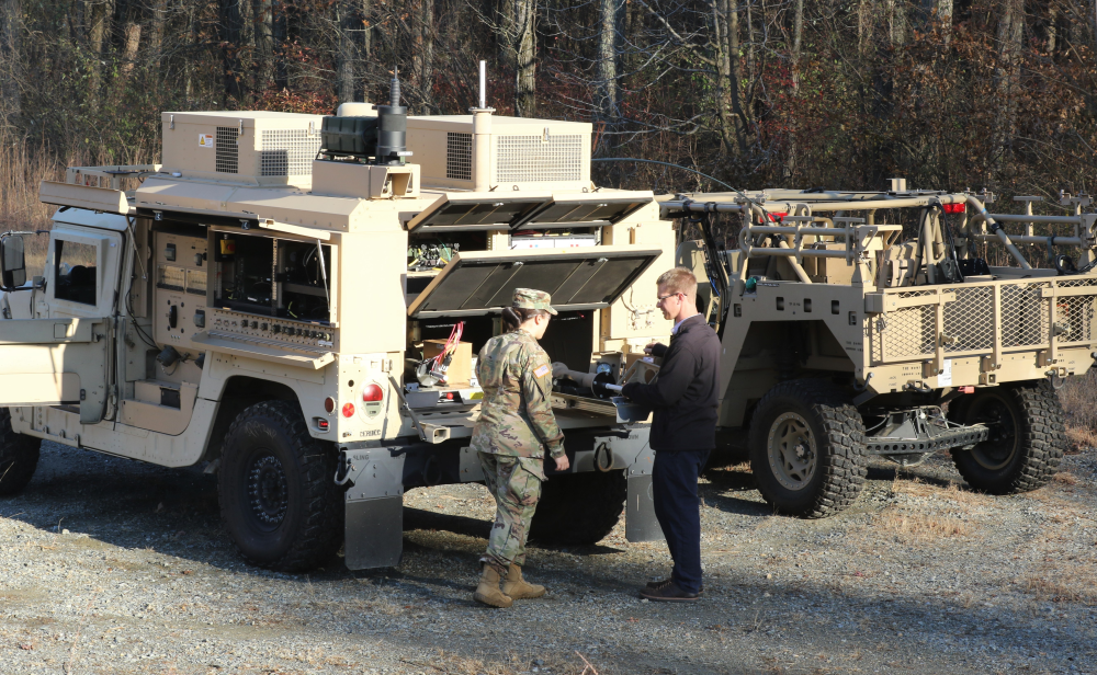 Image of two people conversing behind a mobile military vehicle.