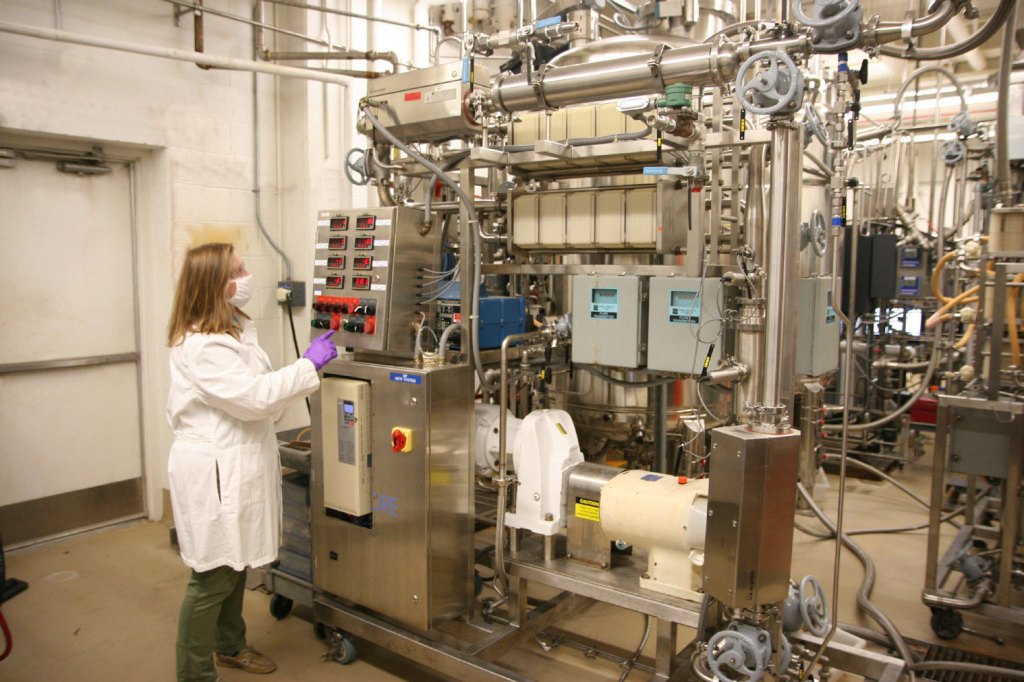 A researcher operates a large machine, which is a biomanufacturing machine.