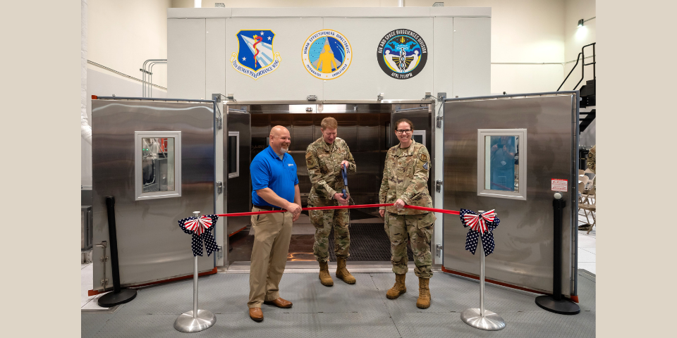 Brig. Gen. Robert K. Bogart, 711th Human Performance Wing commander, cuts a ribbon during the Research Environmental Chamber ribbon-cutting ceremony with the help of Jim Bench, left, president, Russells Technical Products, and Col. Melinda Eaton, acting director, Air Force Research Laboratory’s Human Effectiveness Directorate, at Wright-Patterson Air Force Base, Ohio, May 27, 2025. This state-of-the-art facility, part of AFRL’s Human Effectiveness Directorate, facilitates equipment and human performance evaluations by simulating environmental extremes. (U.S. Air Force photo / Richard Eldridge)