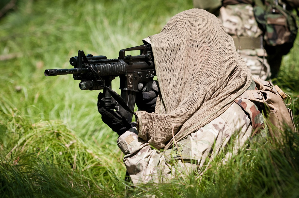 Servicemember with cloth covering over head aiming weapon system.