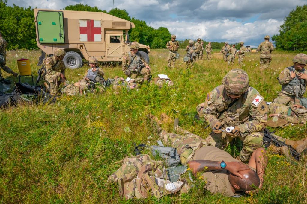 U.S. Army Medics perform first aid on simulated casualties. And ambulance is pared in the background.