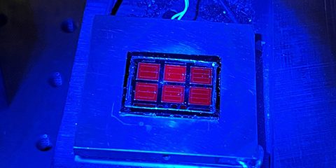 The record-setting solar cell shines red under blue luminescence (photo by Wayne Hicks, NREL).