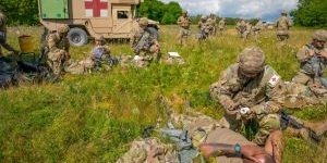U.S. Army Medics perform first aid on simulated casualties. And ambulance is pared in the background.