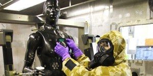 U.S. RDECOM C&B Center scientist Terrence D’Onofrio, in full CB suit protection, outfits Porton Man with sensors prior to a test.