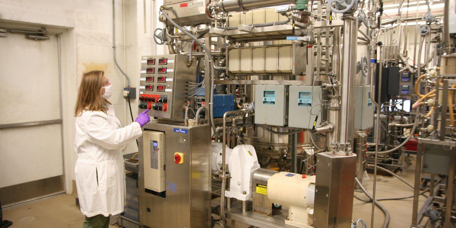 A researcher operates a large machine, which is a biomanufacturing machine.