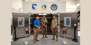 Brig. Gen. Robert K. Bogart, 711th Human Performance Wing commander, cuts a ribbon during the Research Environmental Chamber ribbon-cutting ceremony with the help of Jim Bench, left, president, Russells Technical Products, and Col. Melinda Eaton, acting director, Air Force Research Laboratory’s Human Effectiveness Directorate, at Wright-Patterson Air Force Base, Ohio, May 27, 2025. This state-of-the-art facility, part of AFRL’s Human Effectiveness Directorate, facilitates equipment and human performance evaluations by simulating environmental extremes. (U.S. Air Force photo / Richard Eldridge)