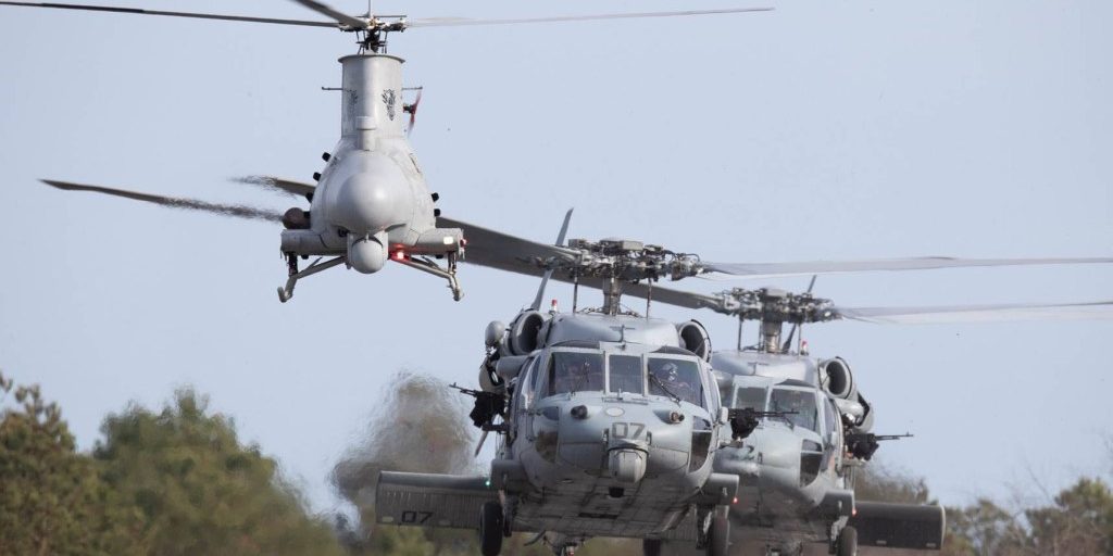 Two helicopters follow behind an unmanned aircraft.