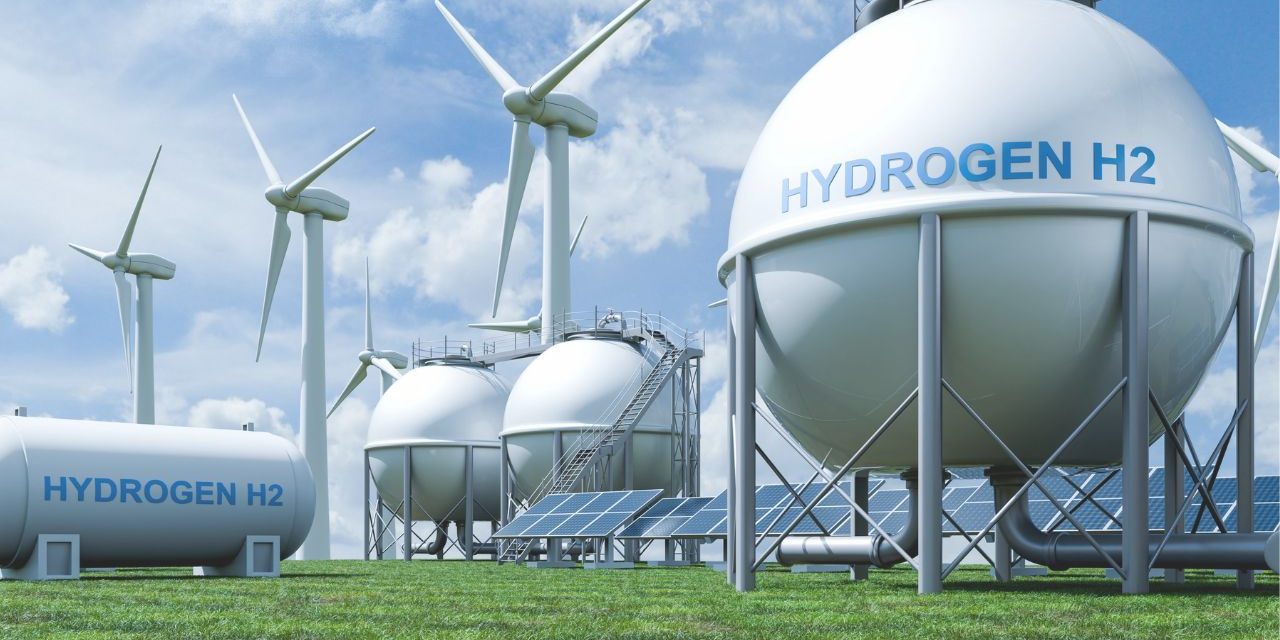 large, white hydrogen gas tanks with windmills and solar panels in the background