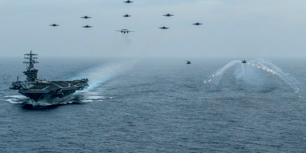 One naval vessel and eleven aircraft traveling over a body of water.