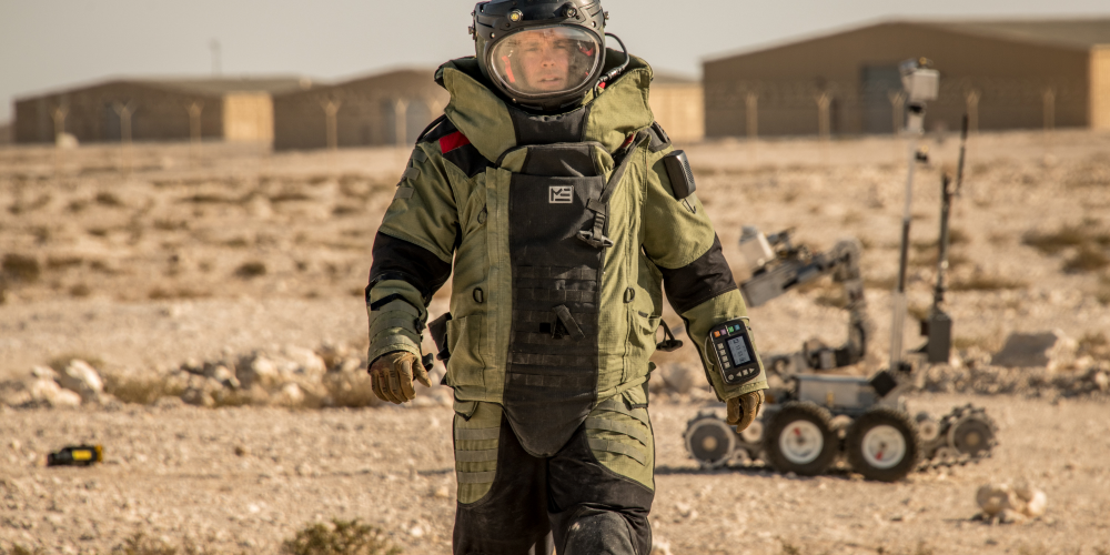 Explosive Ordnance Disposal personnel suited up in a desert landscape.