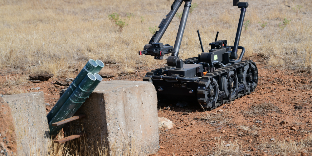 A man-portable tracked robot investigates a suspicious object.