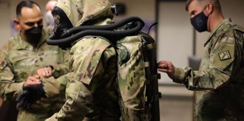 The third-generation TacHazE suit, excluding the rebreather (DEVCOM Soldier Center photo).
Maj. Gen. Antonio Munera, former Commander of the 20th CBRNE Command (right), examines the Tactical All Hazards Ensemble display (center on a manikin) at a technology showcase event hosted by DTRA JSTO at Aberdeen Proving Ground in Edgewood, MD (U.S. Army photo by Marshall R. Mason).