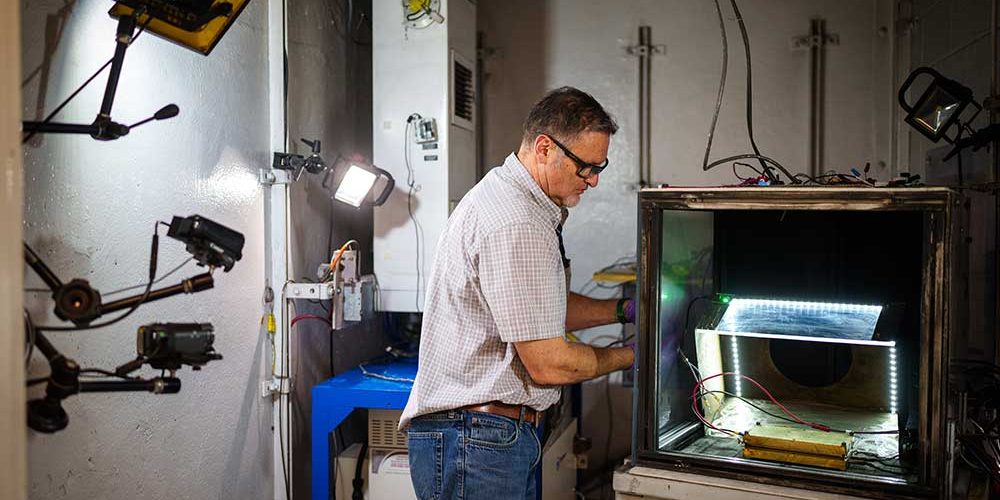 Sandia’s Genaro Quintana prepares a battery for testing in a vault at the Battery Abuse Testing Lab. Sandia’s research on detecting battery failures sooner in electric vehicles was published in the Journal of the Electrochemical Society. (Photo by Craig Fritz)